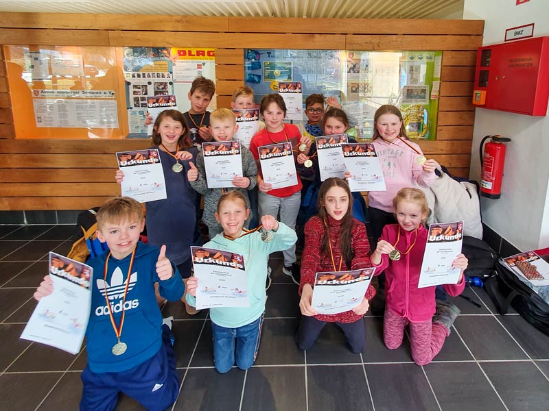Ein Gruppenbild mit Kindern, welche Medaillen und Urkunden präsentieren.