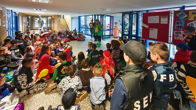 Verkleidete Kinder sitzen im Foyer der Schule.