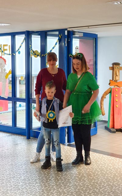 Ein verkleideter Junge mit zwei Erwachsenen im geschmückten Foyer.
