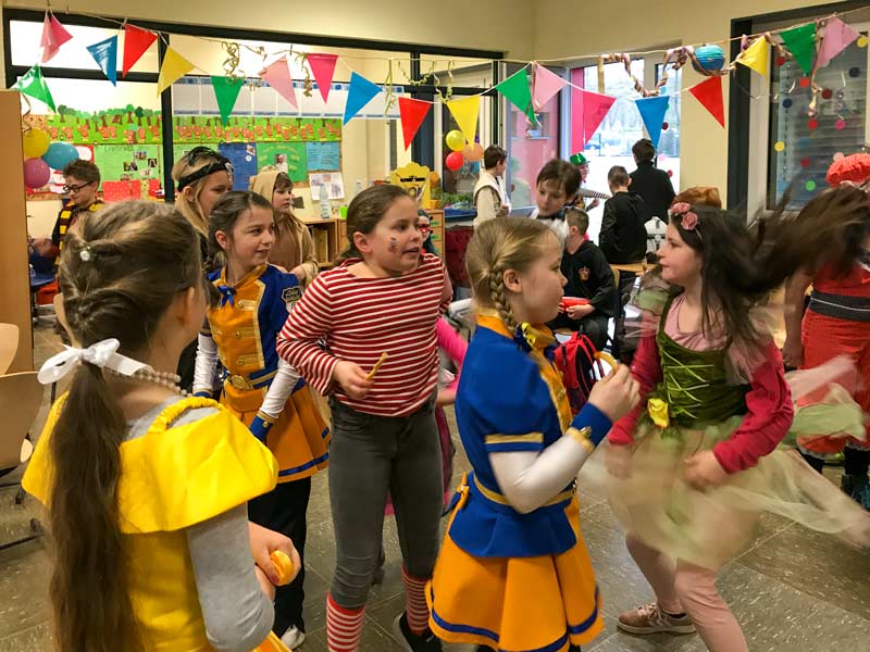 Verkleidete Kinder tanzen im geschmückten Klassenraum.