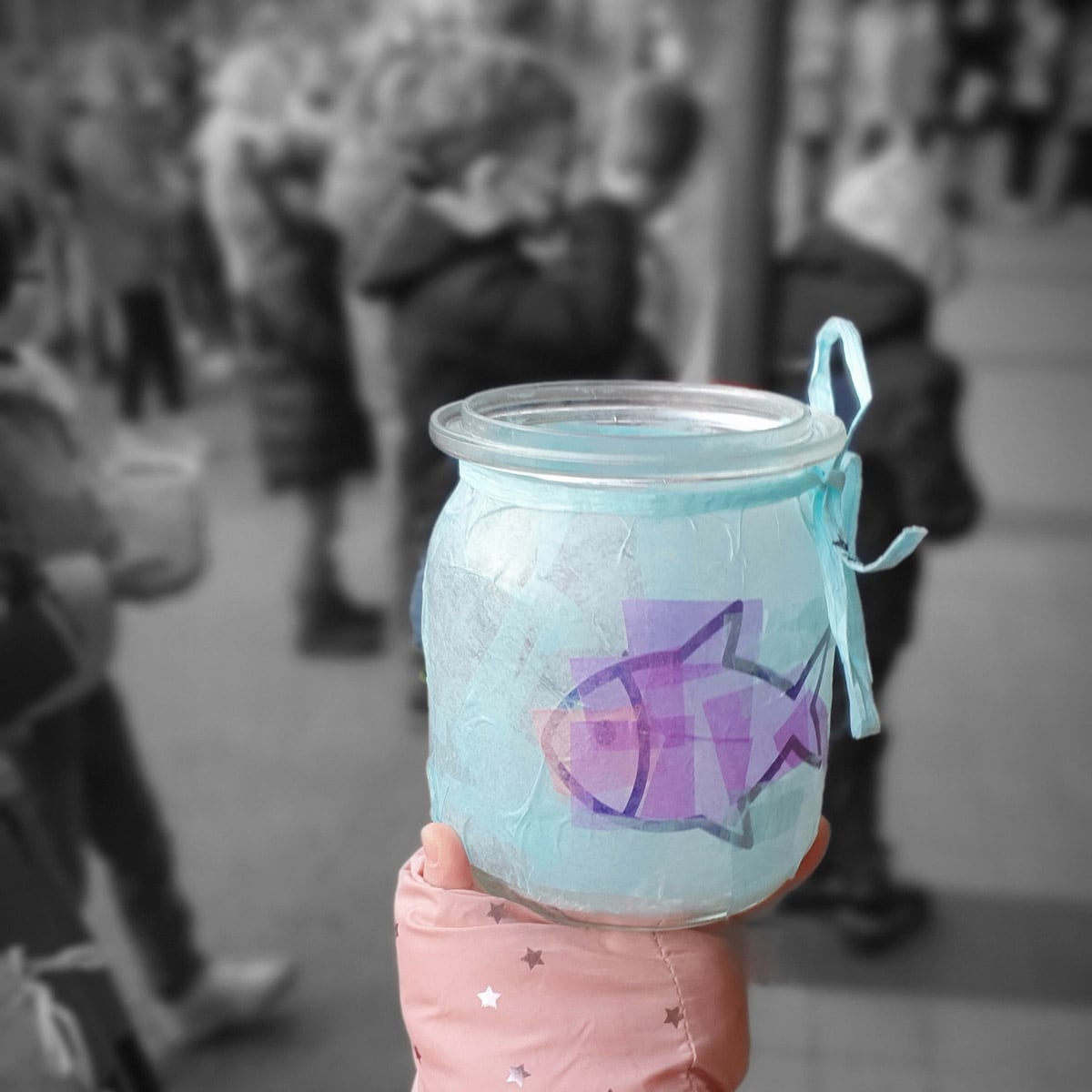 Teelicht in einem Glas in einer Kinderhand.