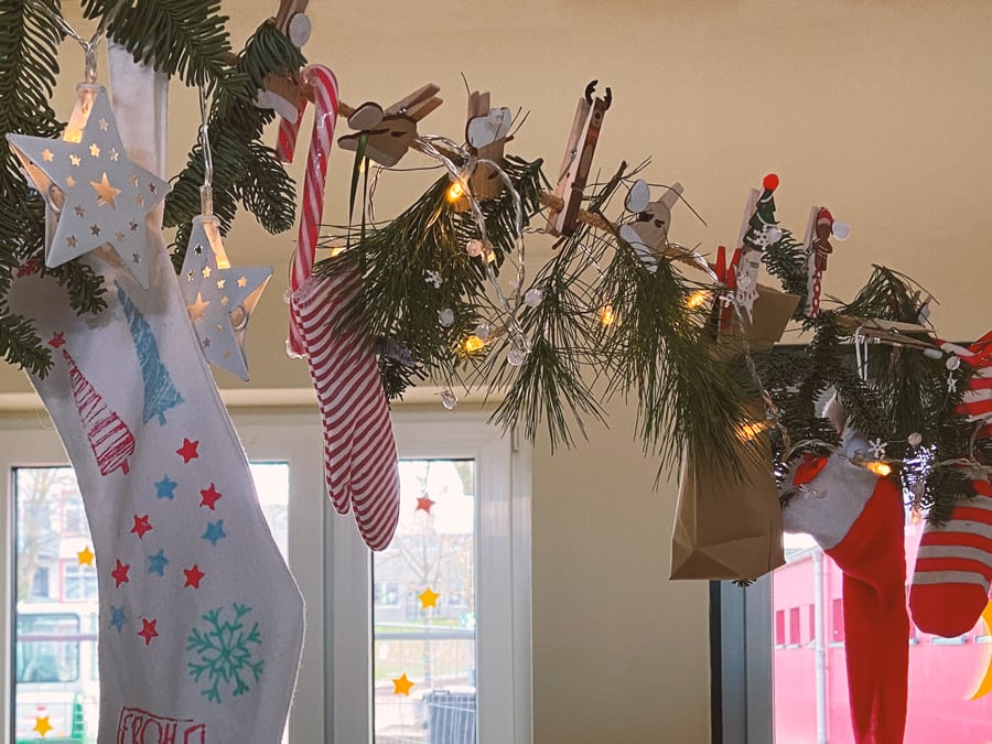 Adventskalender aus Socken, Papiertüten und Tannenzweigen an einer Schnur.