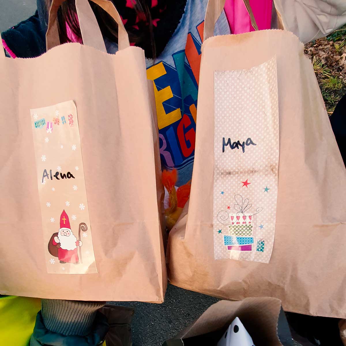 Zwei Geschenktüten mit weihnachtlichen Aufklebern und Namensschildern.