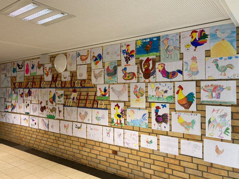 Bilder mit gemalten Hähnen an einer Wand.