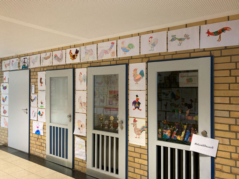 Bilder mit gemalten Hähnen an einer Wand.