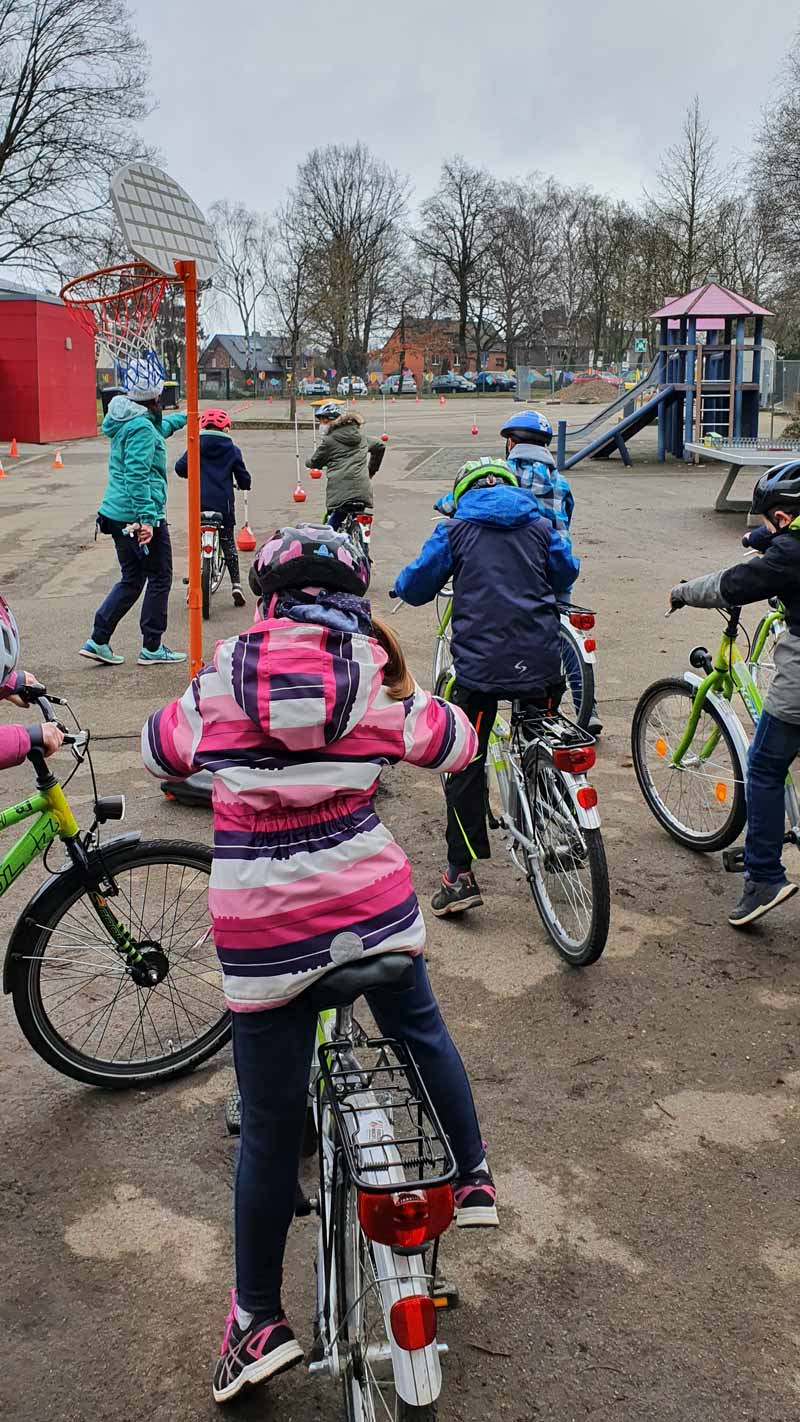 Kinder mit Fahrrädern auf dem Schulhof.