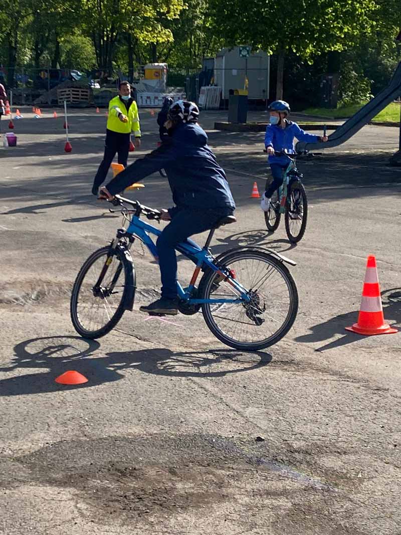 Mehrere Kinder mit Helm fahren auf dem Schulhof mit dem Fahrrad.