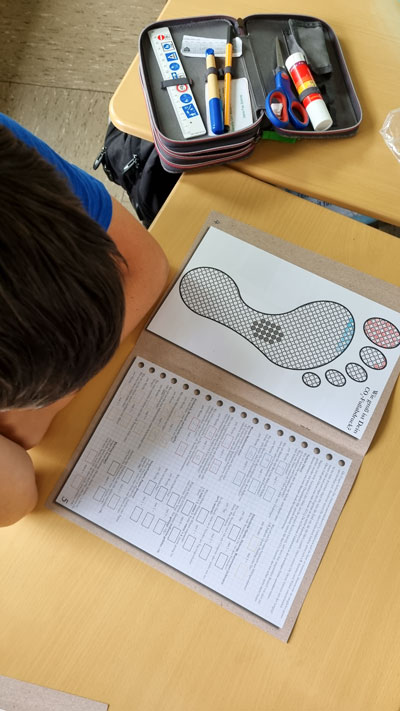 Kinder bearbeiten ihre Arbeitsblätter am Tisch.