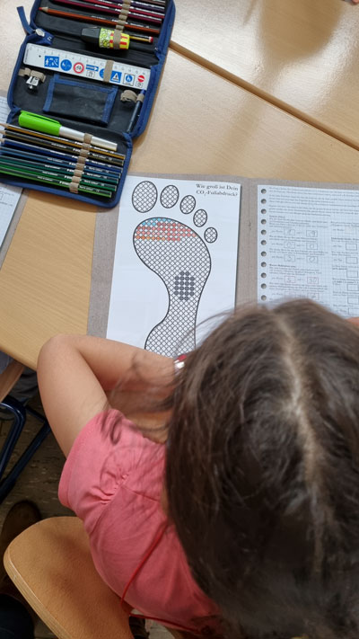 Kinder bearbeiten ihre Arbeitsblätter am Tisch.