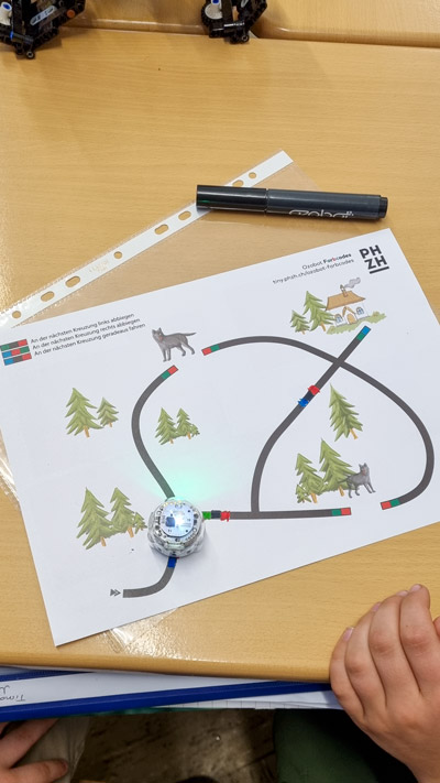 Farbige Programmierskizzen mit Minirobotern liegen auf den Klassentischen.