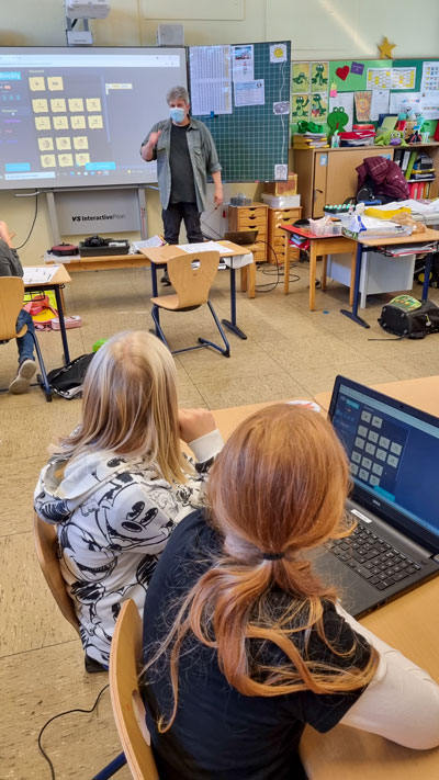 Kinder im Klassenzimmer sitzen vor Computern.