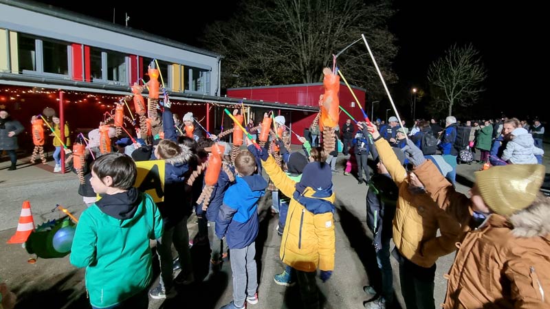 Eine große Gruppe Kinder auf dem Schulhof mit ihren Laternen.