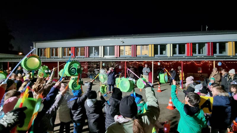 Eine Gruppe Kinder mit ihren Laternen vor dem Schulgebäude.