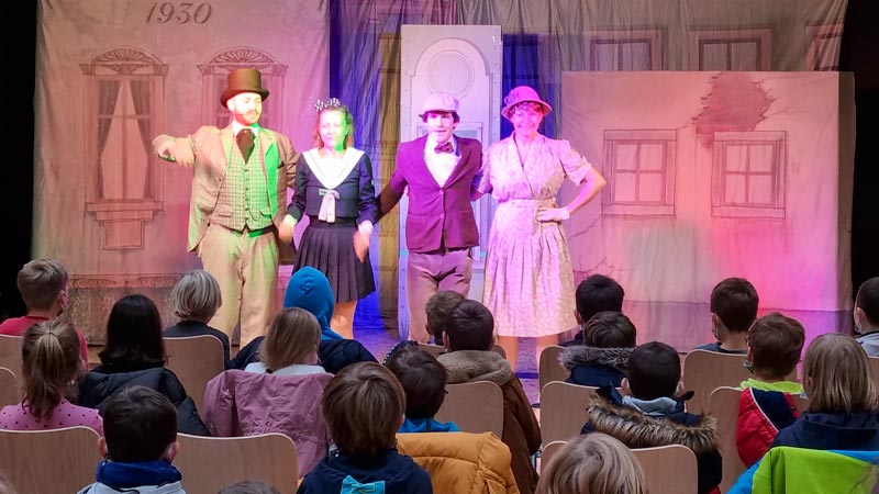 Vier Theaterschauspieler in altmodischen Kostümen auf der Bühne.