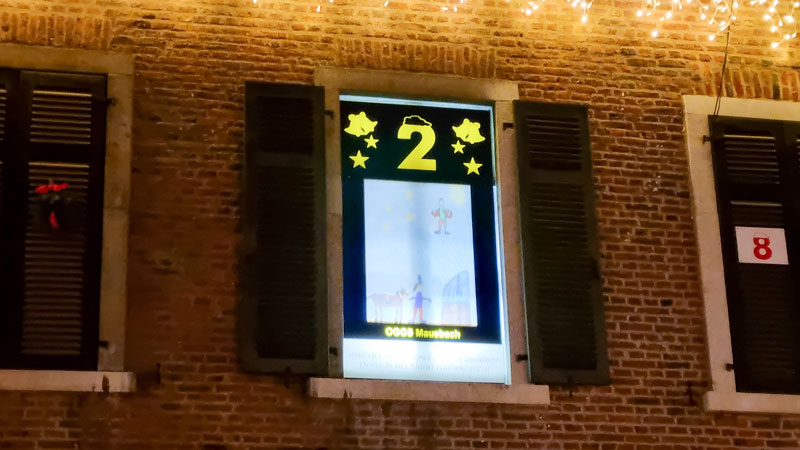 Geöffnetes Fenster mit beleuchtetem Fensterbild und einer großen gelben Zwei.