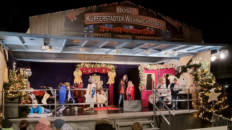 Weihnachtlich dekorierte Bühne, auf der Kinder ein Schauspiel vorführen.