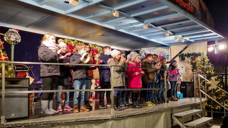 Kinderchor auf einer weihnachtlichen Bühne.
