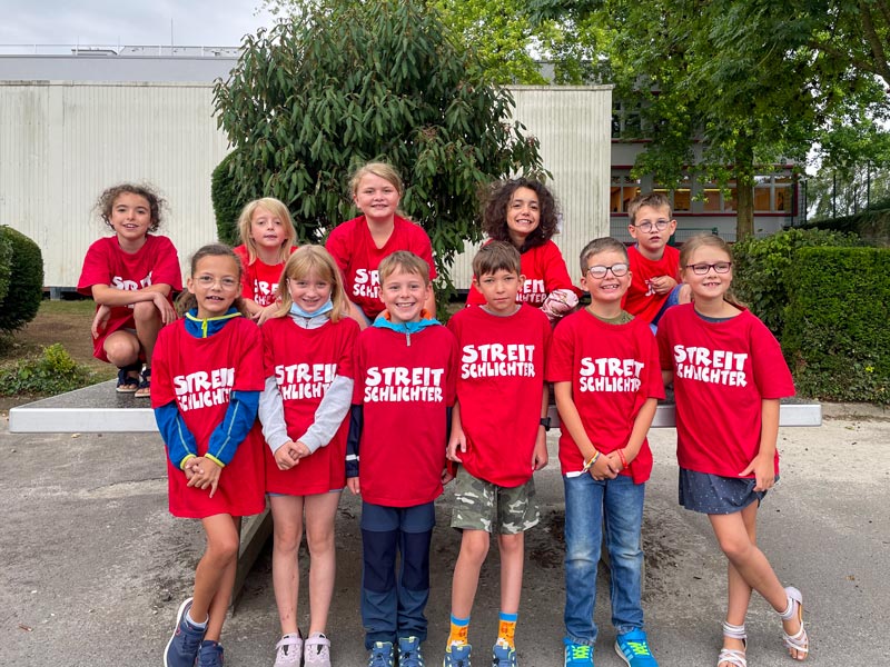 Gruppenfoto der Streitschlichter*innen in roten T-Shirts, mit der Aufschrift: Streitschlichter.
