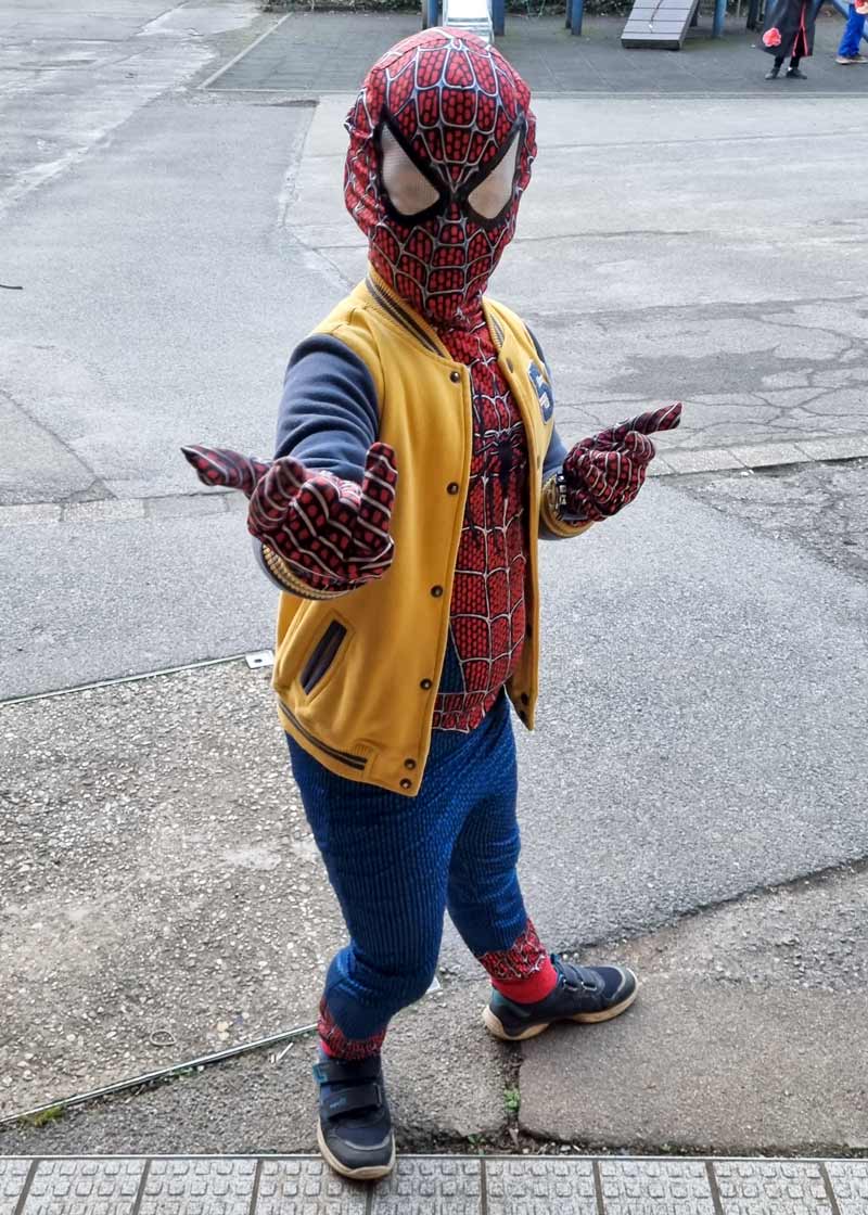 Ein Kind im Spiderman-Kostüm auf dem Schulhof.