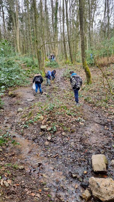 Eine Kindergruppe im Wald, die Müll aufsammeln.