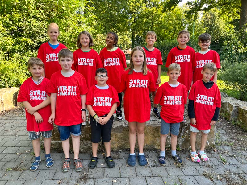 Gruppenfoto der Streitschlichter*innen in roten T-Shirts, mit der Aufschrift: Streitschlichter.