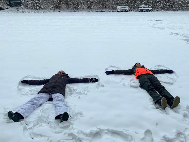 Zwei Personen liegen im Schnee und bilden Schneeengel.