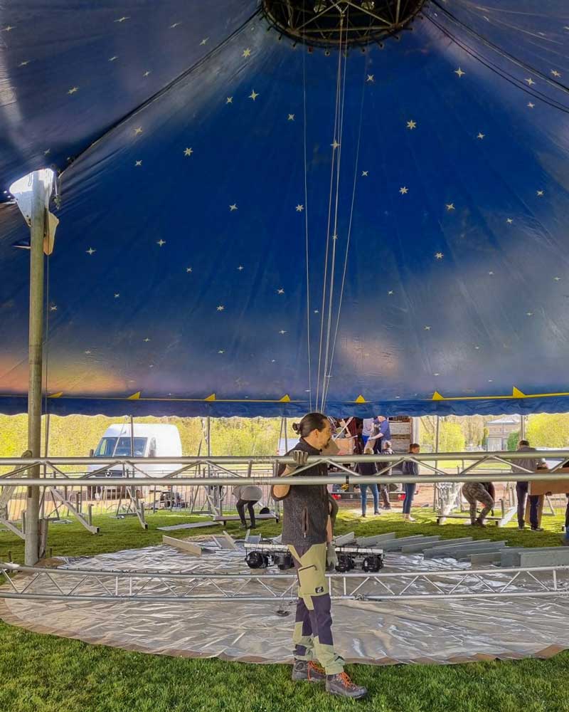 Elternhelfer beim Aufbau der Zirkusmanege unter dem blauen Zeltdach.