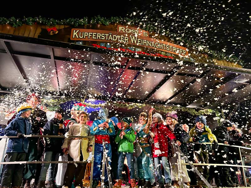 Kindergruppe abends auf der Bühne im künstlichen Schneegestöber.