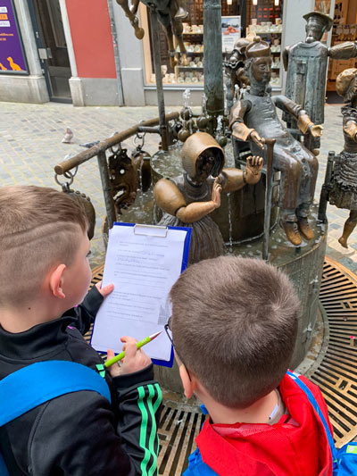 Zwei Schüler am Puppenbrunnen lösen ein Rätsel.